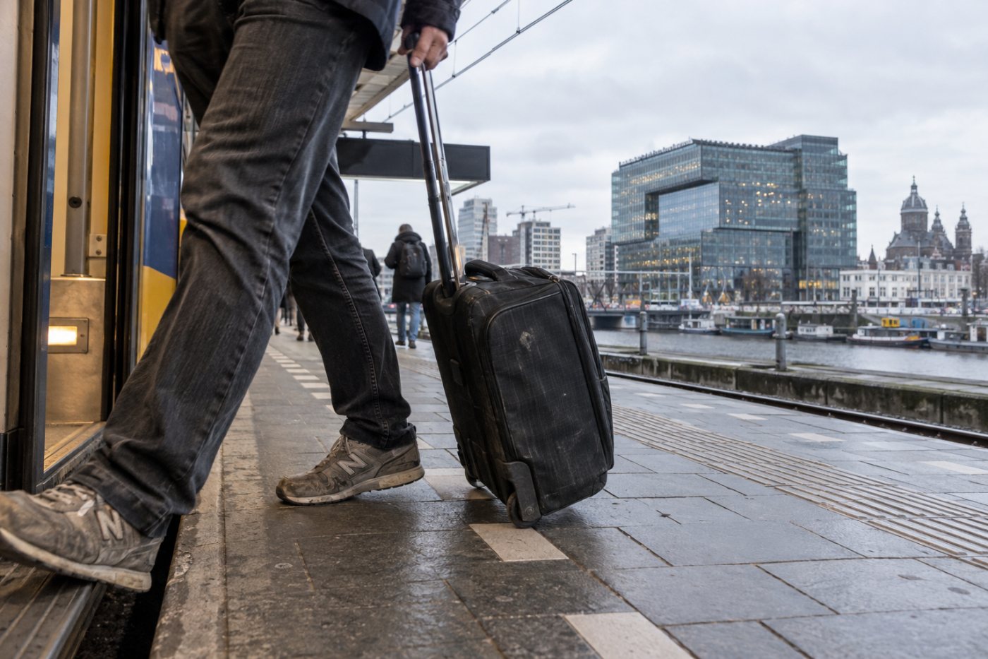 Reizigers op weg naar het Amsterdamse hoofdkantoor van Booking.com verbeelden het extra reizen dat de ondernemingsraad aanvoert.
