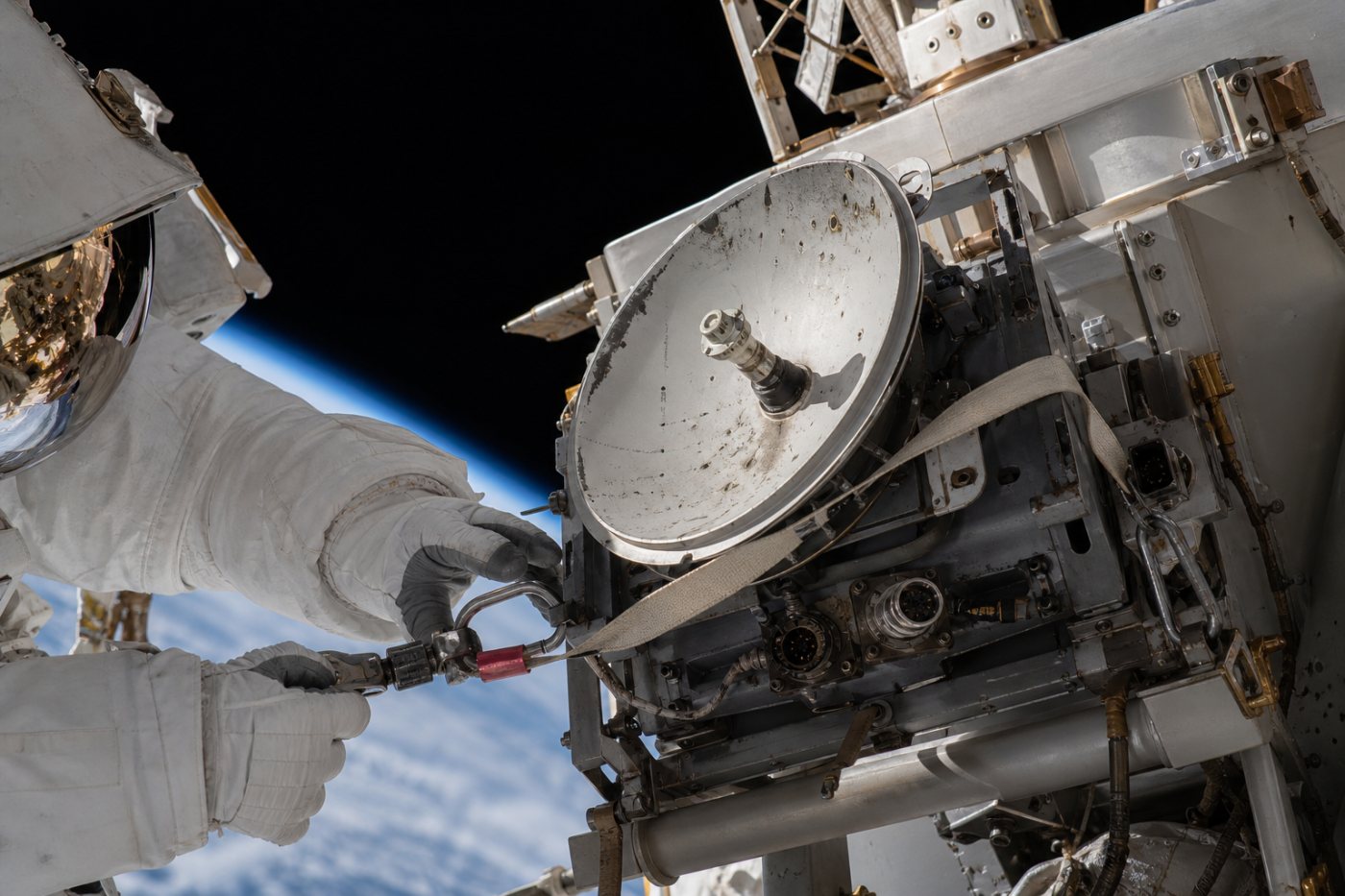 Anil Menon transports the spare ISS antenna on Canadarm2 while Sophie Adenot moves toward the Z1 truss installation site.
