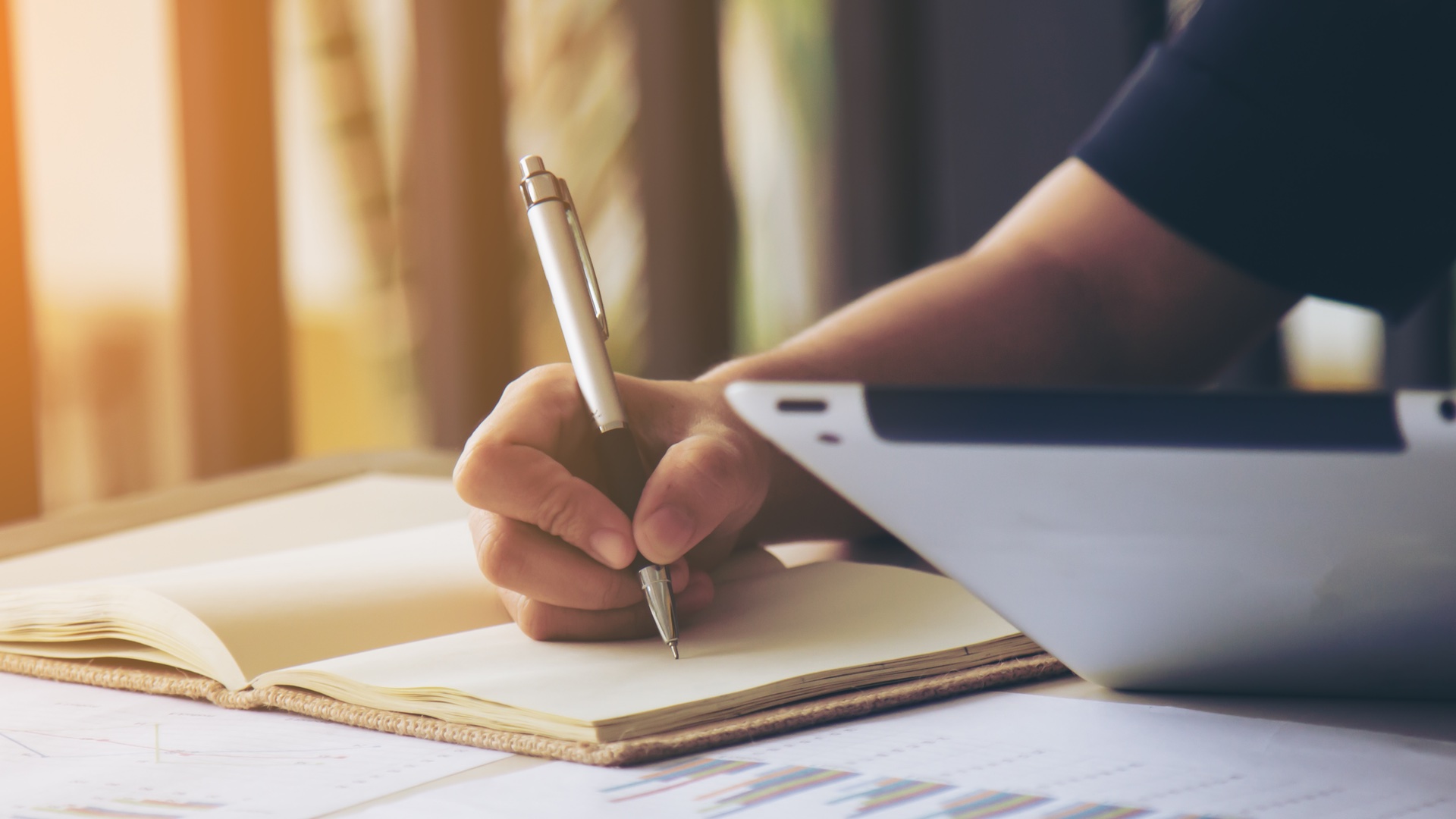 Рука человека, держащая ручку, пишущая на бумаге.