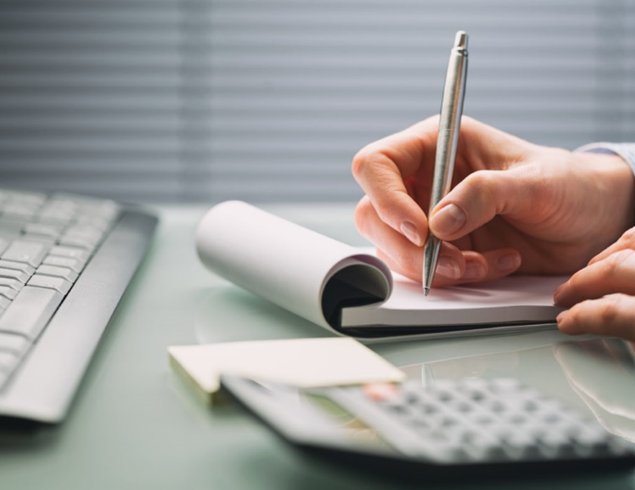 Человек пишет на клавиатуре компьютера с помощью ручки, электроника и аппаратура.