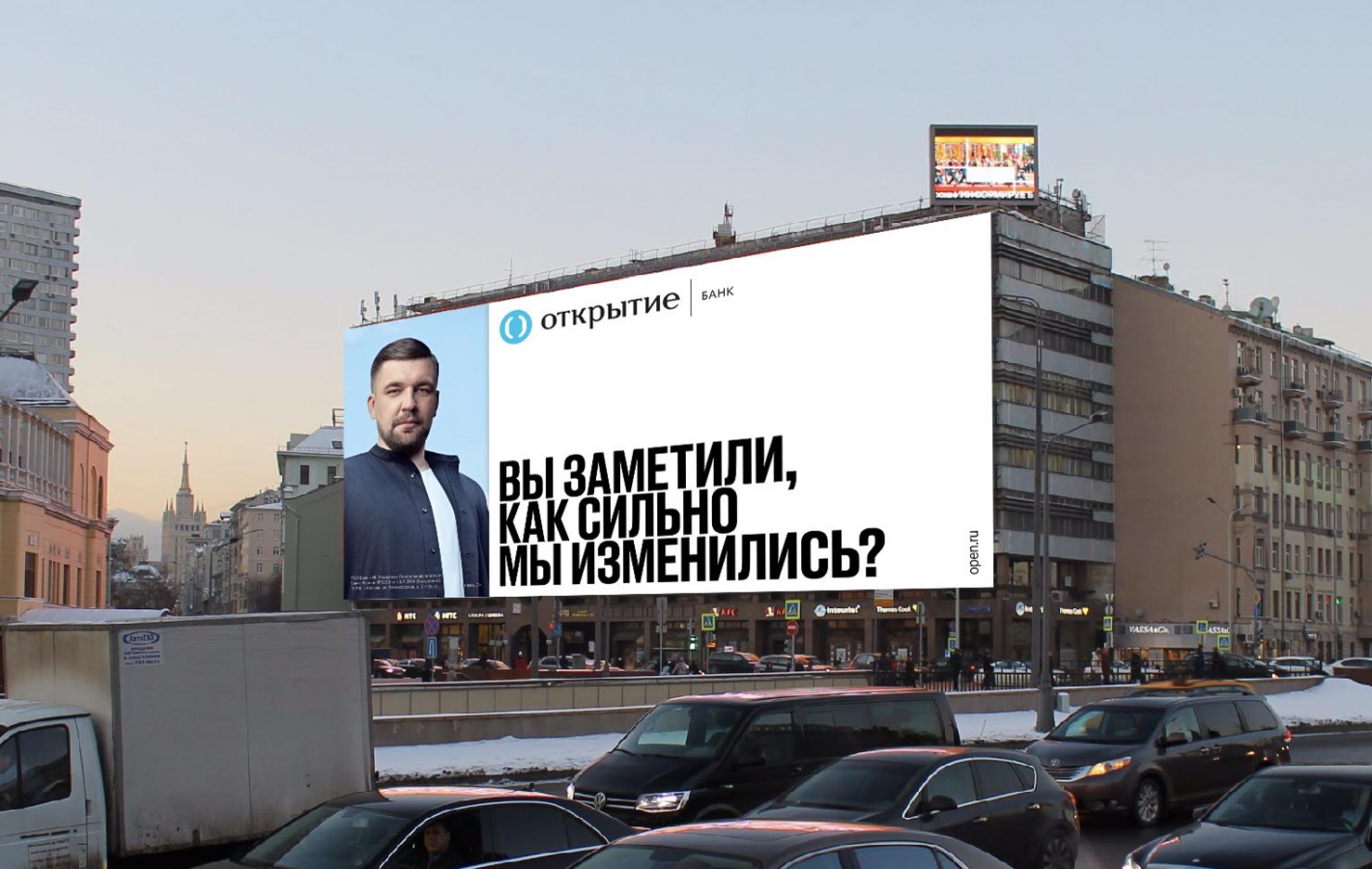 Реклама на строении: взрослый мужчина у автомобиля у билборда и грузовика.