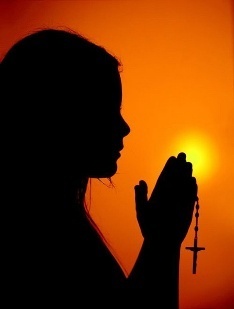 Женщина взрослого возраста молится в силуэте силуэта.