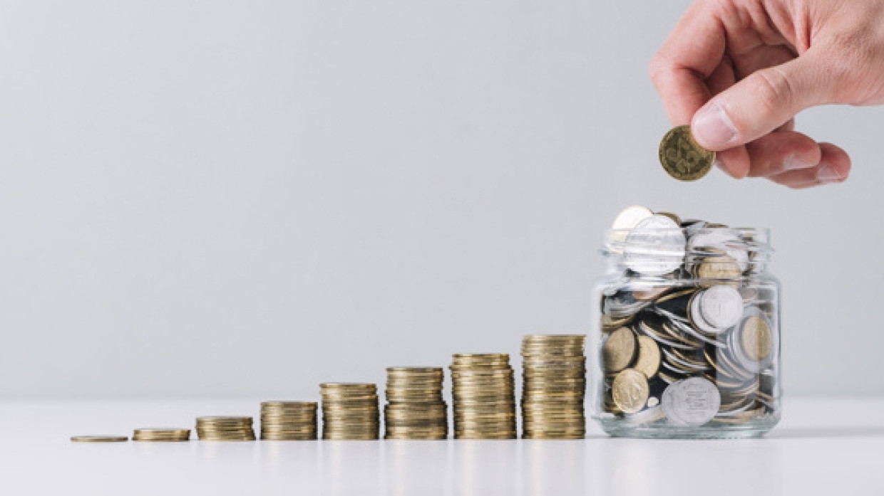 Маленький ребенок с монетой в жестяной банке, символизируя накопления.