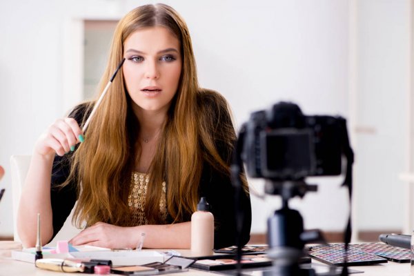 Фотография человека с кистью, инструментом на голове, изображающим лицо.