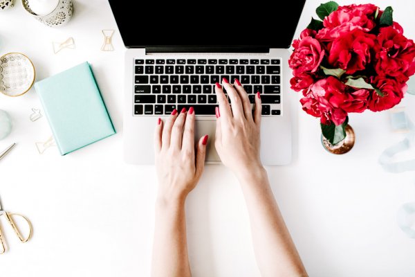 Женщина-взрослая на ноутбуке с клавиатурой рядом с красной розой.