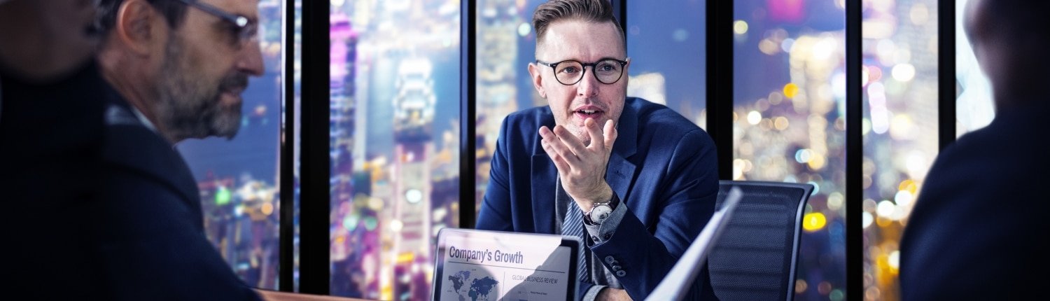 Мужчина в очках и наручных часах, сосредоточенный взгляд, в публичном месте.