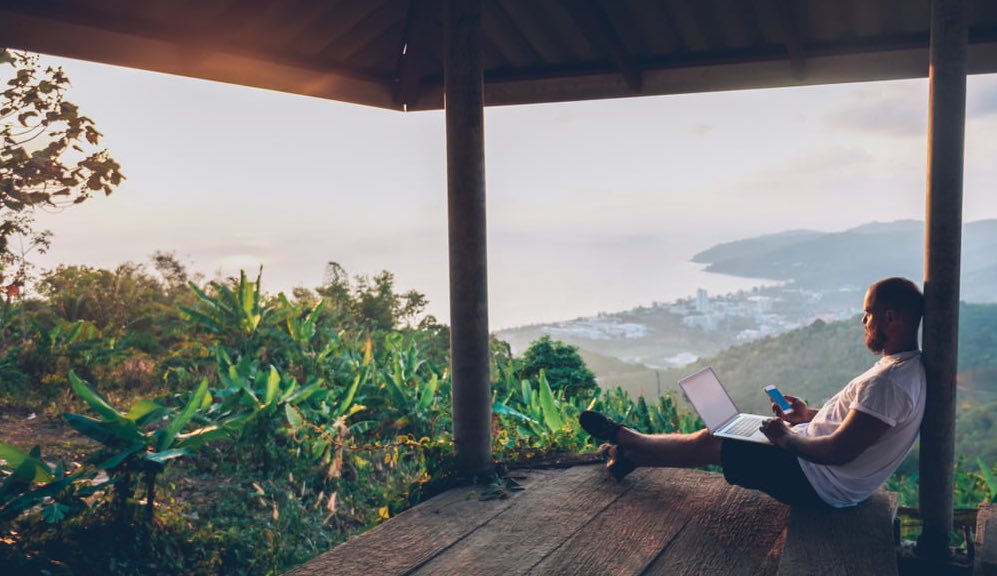 Архитектурное здание отеля с мужчиной, сидящим на террасе курорта.