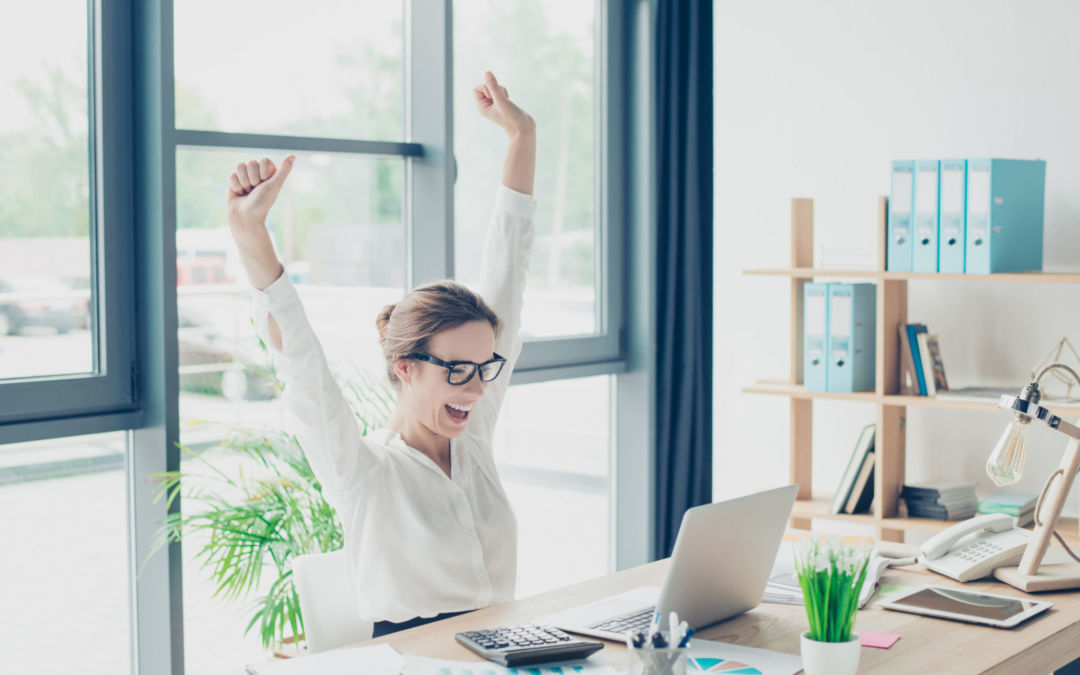 Голова улыбающегося человека с выражением победы за компьютером и ноутбуком.