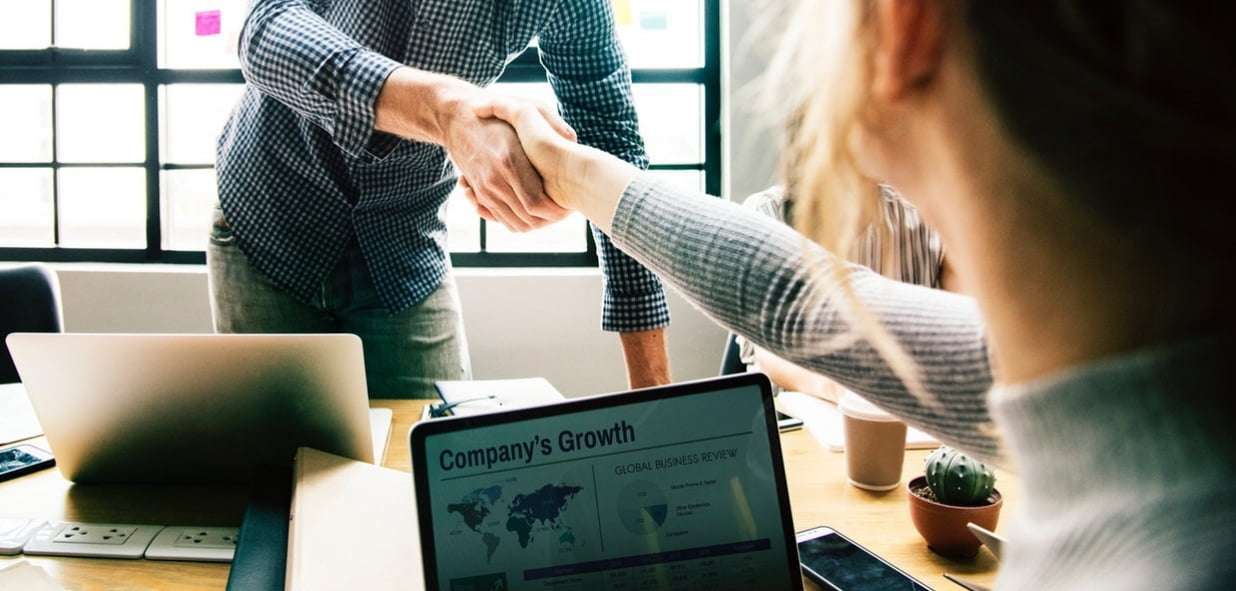 Мужчина работает на ноутбуке рядом с женщиной, у которой в руках мобильный телефон.