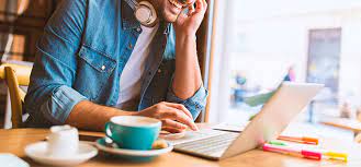 Электроника: человек с кофе в руках за ноутбуком и компьютером.