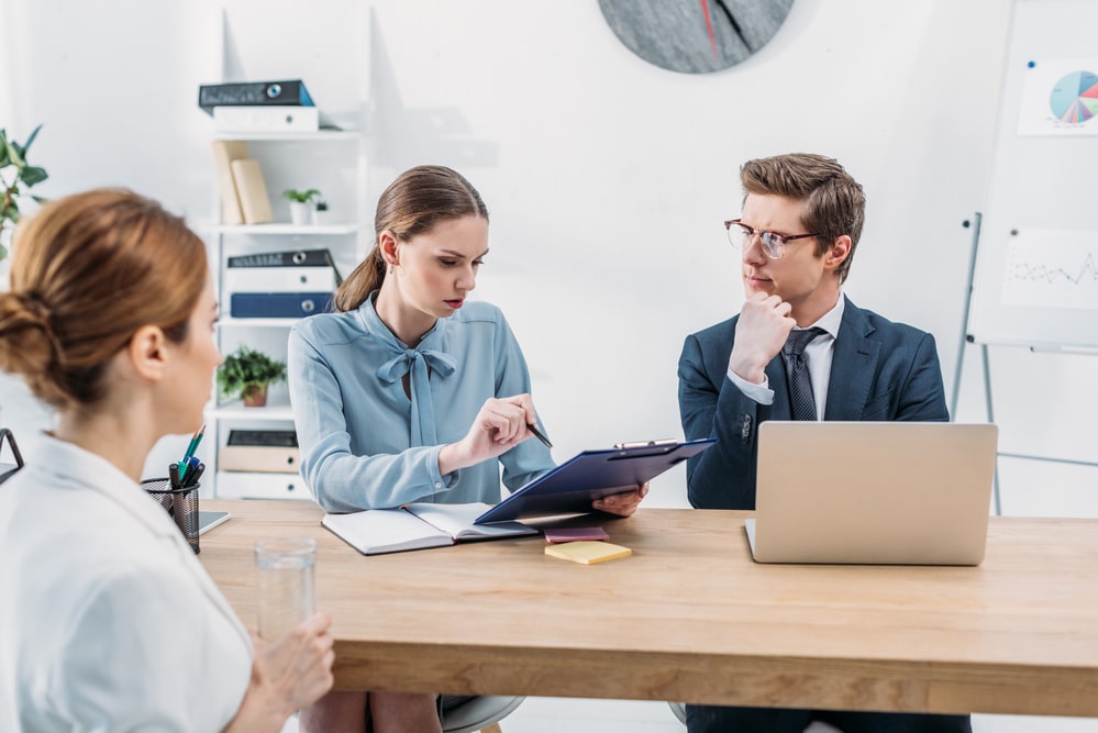 Мужчина обсуждает деловые вопросы за ноутбуком, держа в руках книгу и ручку.
