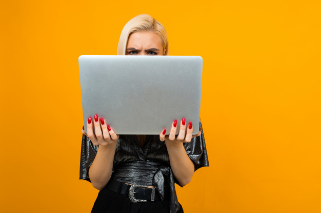 Человек с удивленным выражением лица за ноутбуком на фоне компьютерной техники.