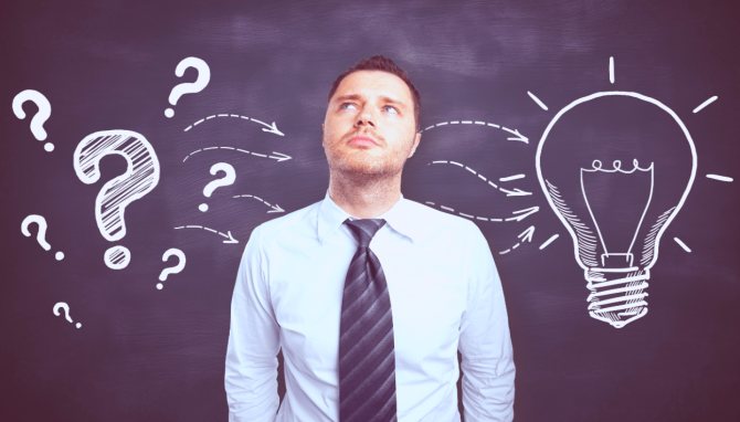 Фотография взрослого мужчины в дорожной рубашке и галстуке перед доской.