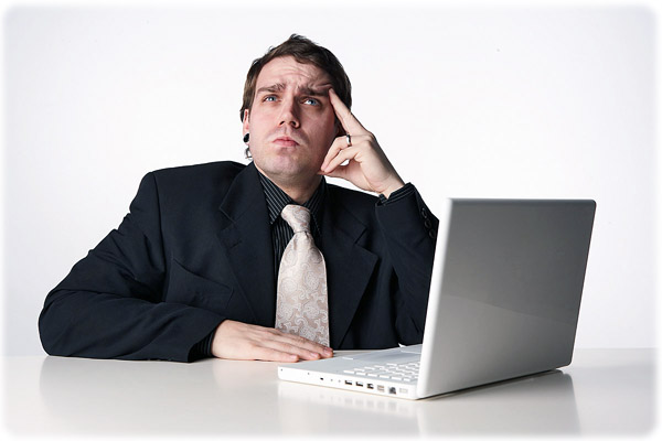 Ноутбук на рабочем столе с человеком в деловом костюме и галстуке.