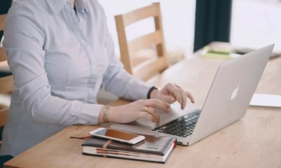 Ноутбук сотрудника, мужчина пишет ручкой, клавиатура, мобильный, деловой исполнитель.