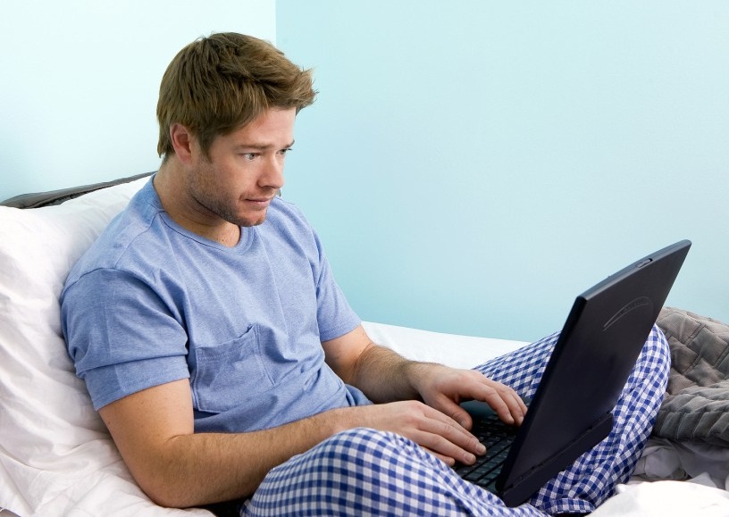 Компьютерный мужчина, сидящий за ноутбуком, сосредоточенно смотрит на экран.