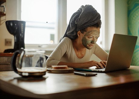 Мужчина на рабочем столе с ноутбуком, мобильным телефоном и чашкой кофе.