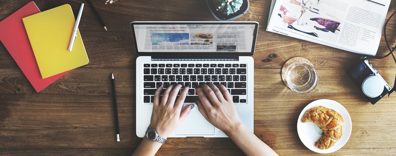 Ноутбук на столе с ручкой, компьютер, электроника, текст и мебель.