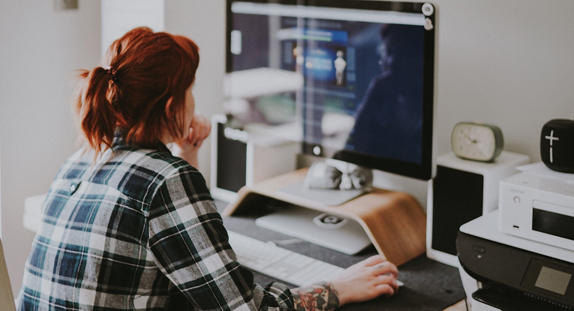 Взрослая женщина в рубашке с лицом на фоне мебели и стола.