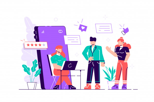 Взрослый мужчина сидит среди толпы за компьютером, окруженным растениями.