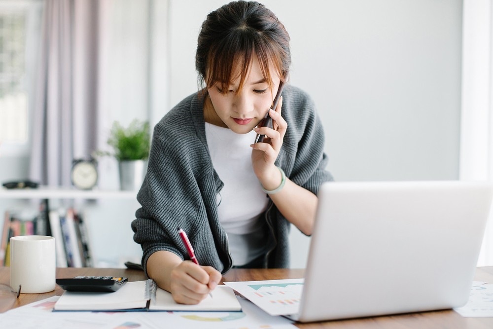 Человек с пеном пишет на ноутбуке, лицо на фоне компьютера.