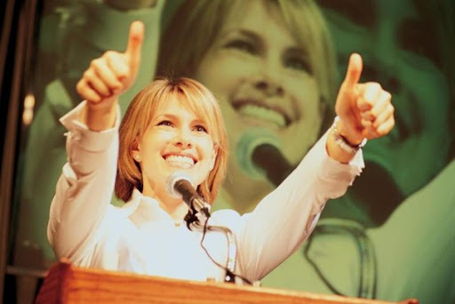 Крупный план многолюдной аудитории, уверенная рука с вытянутым пальцем.