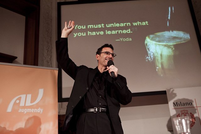 Мужчина-взрослый аудитор с микрофоном на семинаре перед толпой людей.