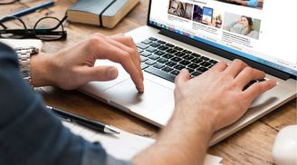 Человек, взрослый мужчина печатает на ноутбуке с клавиатурой компьютера.