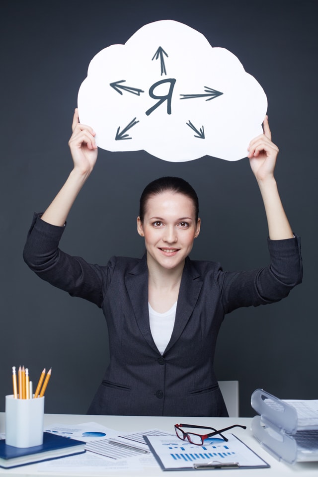 Взрослая женщина в очках за столом, глядящая на текст, портрет лица.