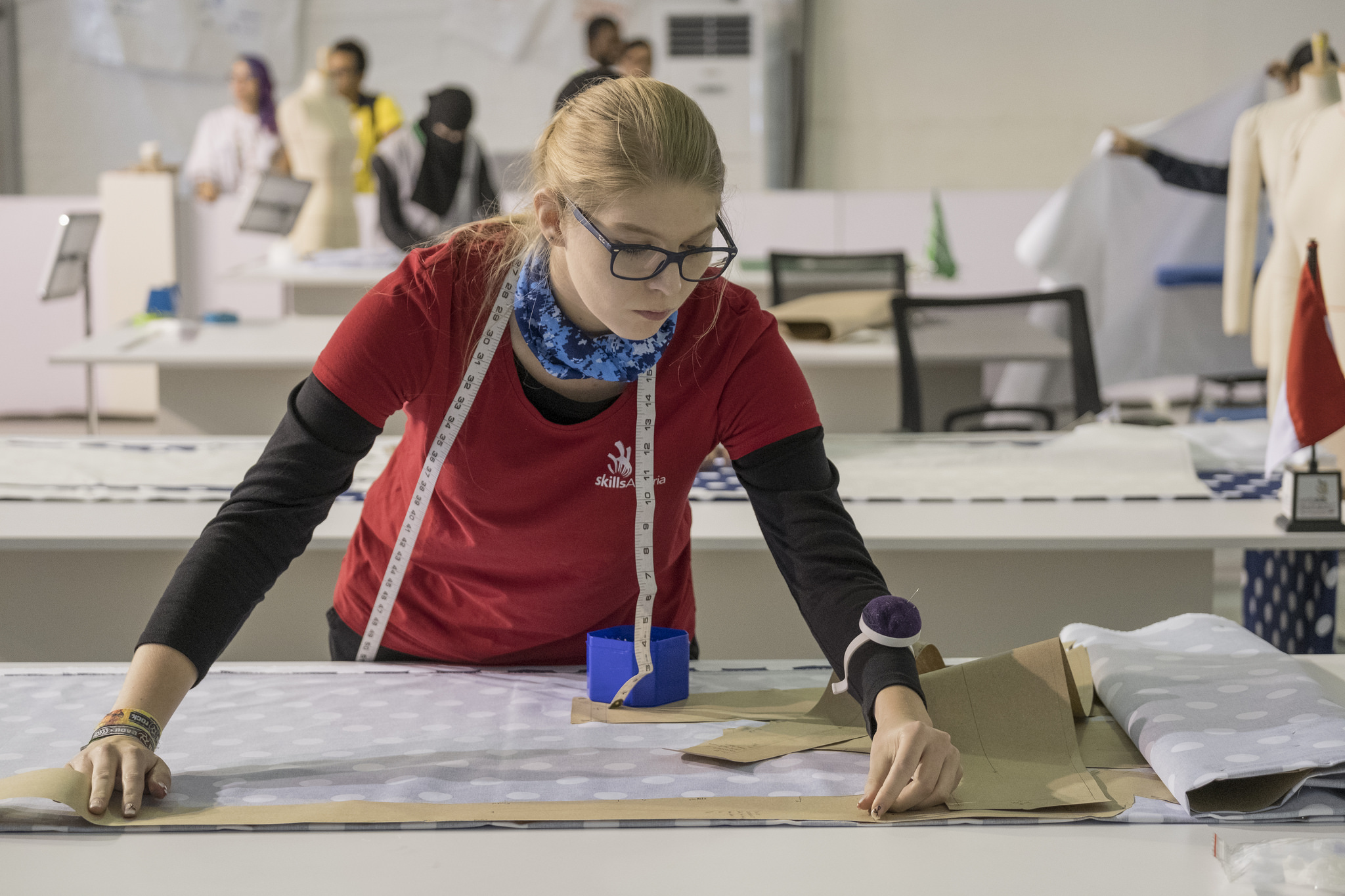 Студент с очками и аксессуарами, сидящий на стуле с мебелью. Фокус на лице и голове.