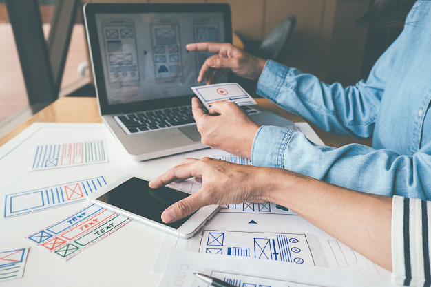 Человек работает на ноутбуке с монитором и мобильным телефоном рядом.