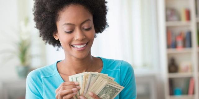 "Close-up of person's face with hand holding money - financial success concept"