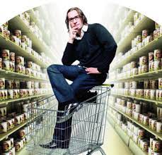 Мужчина на полках магазина с тележкой для покупок, одевается в магазине.