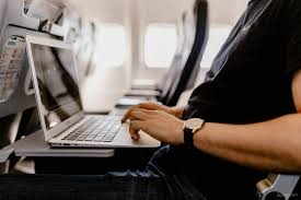 Мужчина использует ноутбук с компьютерной клавиатурой и монитором на фоне.