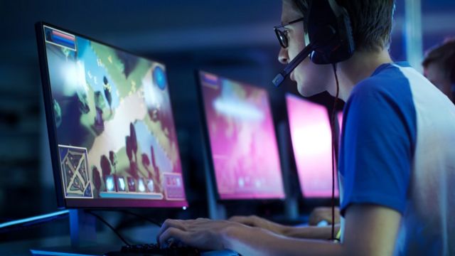 Человек играет в видеоигры на мониторе с наушниками и аксессуарами.