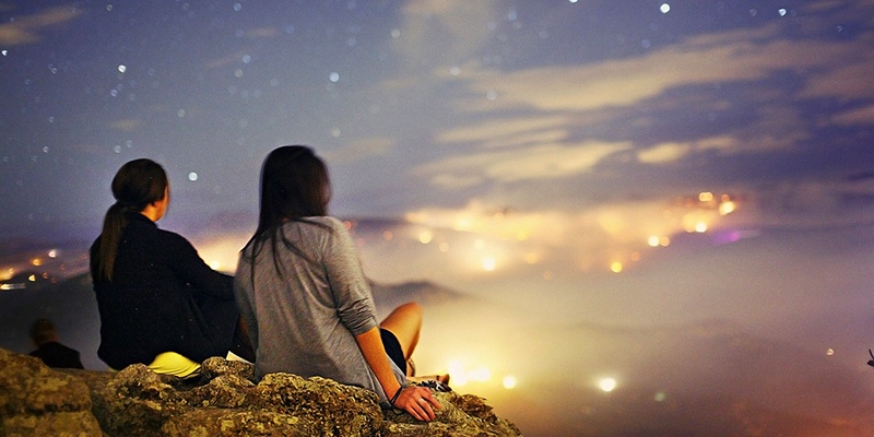 Ночная фотография природы с женщиной на фоне ночного неба и скал.