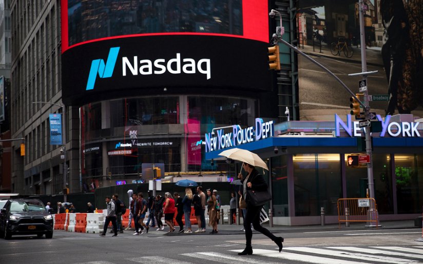 Девушка в городе идет по дороге с сумкой, окруженная автомобилями и светофором.