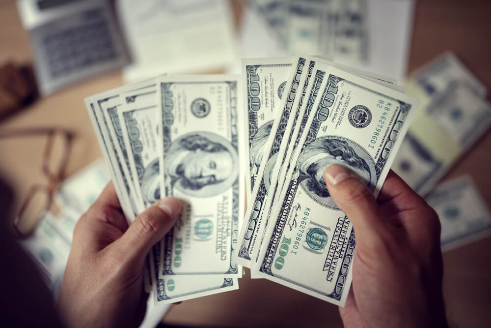 Человек с долларами на лице: крупный план головы с изображением денег.