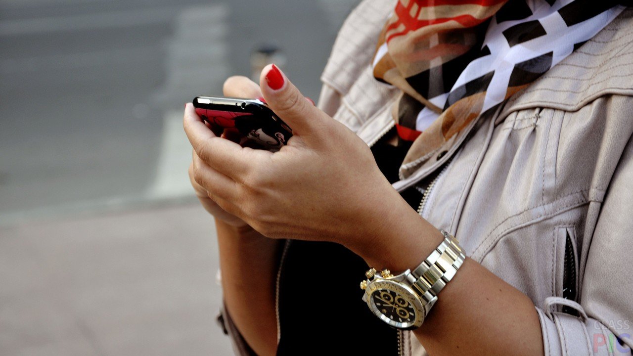 Электроника: человек с мобильным телефоном, текстит на смартфоне с часами на руке.