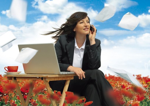 Женщина в блейзере с чашкой кофе, работающая на ноутбуке, в фотостудии.