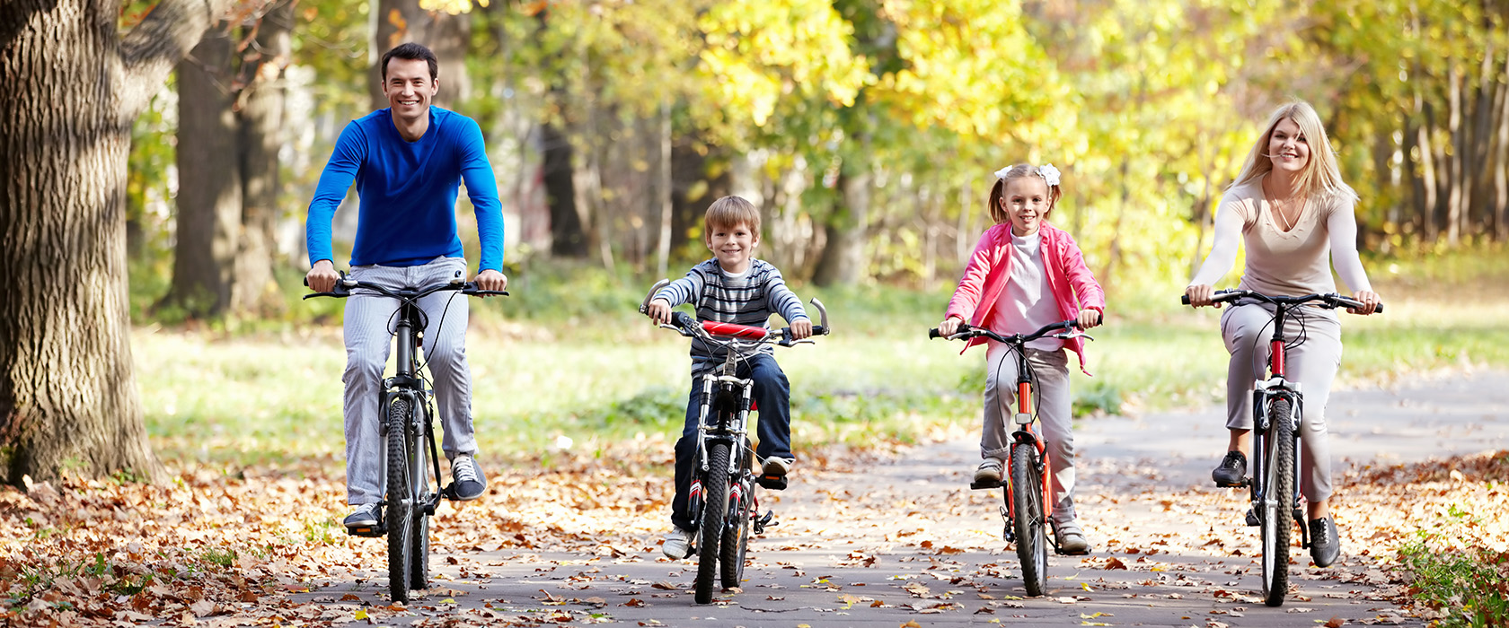 Мальчик на велосипеде на фоне взрослой женщины и других людей.