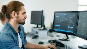 Мужчина за столом с монитором, на фоне доски, мебелью. (Furniture, Table, Monitor, Screen, Adult, Male, Man, Blackboard, Desk)