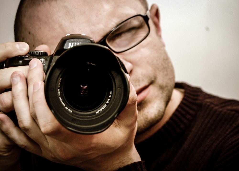 Фотография взрослого мужчины с камерой, созданная профессиональным фотографом.