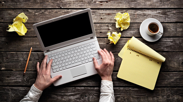 Мужчина на ноутбуке за столом - изображение с компьютером, электроникой и кофейной чашкой.