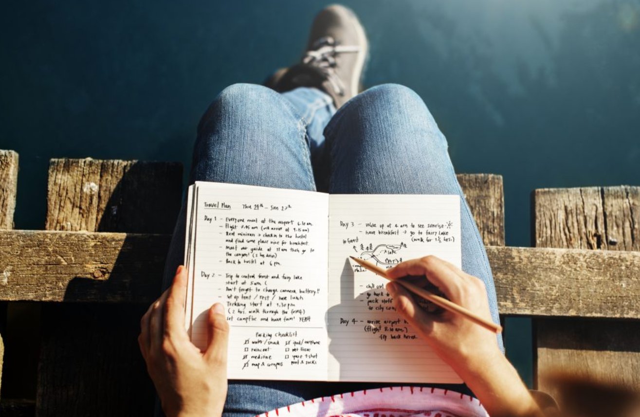 Женщина в одежде читает книгу с ручкой в руке.