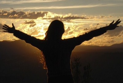 Женщина счастлива и триумфально поднимает руку в перчатке на фоне неба.