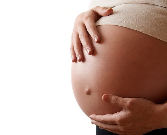 Персона держит ручку младенца на животе. Головы не видно.