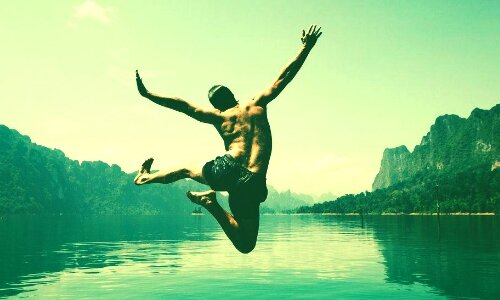 Мужчина в шортах купается в озере летом на свежем воздухе.