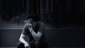 Мужчина сидит и задумчиво смотрит в дым от сигареты.