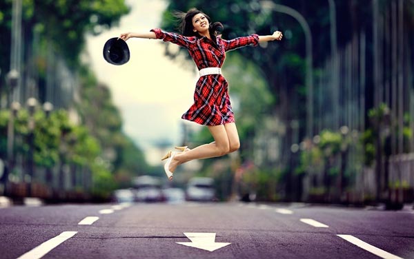 Девушка подросток в прыжке с улыбающимся лицом и поднятой головой.